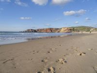 people are on the beach with the tide coming in and footprints in the sand leading to the ocean