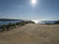 a motorcycle on dirt road near the ocean under sun light and blue skies, on a sunny day