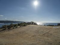 a motorcycle on dirt road near the ocean under sun light and blue skies, on a sunny day