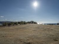 a motorcycle on dirt road near the ocean under sun light and blue skies, on a sunny day