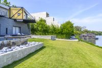 an empty backyard overlooking a river, and two houses on a hill with steps that lead to a small swimming pool