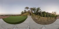 a photo of a backyard with stone floors, grass, and stairs, and an outdoor artificial putting area for a golf