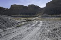 dirt road leads to large rocks in a badlands landscape, with a sign posted at the end