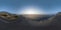 the road goes past the cliff with the ocean in the background, at dusk, near a cliff