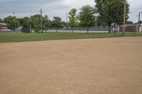 a baseball diamond with a catchers box behind it on the grass field in front of trees