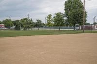 a baseball diamond with a catchers box behind it on the grass field in front of trees