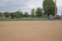 a baseball diamond with a catchers box behind it on the grass field in front of trees