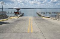 the sidewalk is empty and empty by the water, where there are boats, a pier, and a large body of water