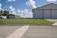 an empty lot with several garages in front of it, and grass behind them