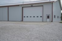 a couple of garages sitting in a gravel parking lot near two vans parked outside