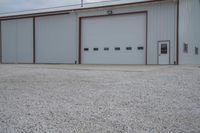 a couple of garages sitting in a gravel parking lot near two vans parked outside