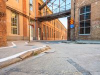 an empty alley next to the road under a metal bridge in an old brick building