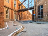an empty alley next to the road under a metal bridge in an old brick building
