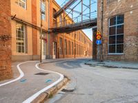 an empty alley next to the road under a metal bridge in an old brick building