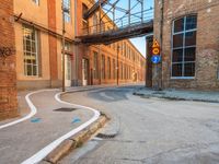 an empty alley next to the road under a metal bridge in an old brick building