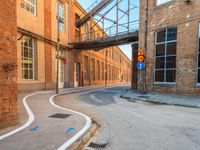 an empty alley next to the road under a metal bridge in an old brick building