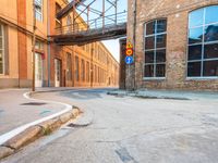 an empty road on a city street with a pedestrian bridge over it, which leads to a car that is driving on a ramp below