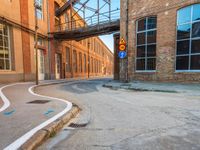 an empty road on a city street with a pedestrian bridge over it, which leads to a car that is driving on a ramp below