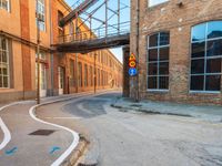 an empty road on a city street with a pedestrian bridge over it, which leads to a car that is driving on a ramp below