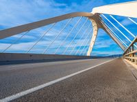 a large metal bridge spanning a highway under a cloudy blue sky on the side of the road