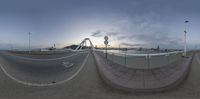 a wide angle shot of an ocean with a suspension bridge at the end of it