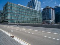 street next to large building and traffic lanes on the left side of it with white dotted lines going through