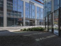 an open courtyard with a sidewalk and building in the background, and a small sign in between two tall glass buildings