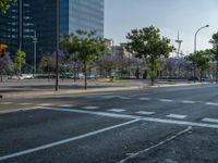 an empty street in front of a building and trees on the other side of the road