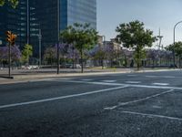 an empty street in front of a building and trees on the other side of the road