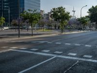 an empty street in front of a building and trees on the other side of the road