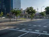 an empty street in front of a building and trees on the other side of the road