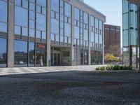 a empty parking area with large windows and a sidewalk in front of a building with lots of glass