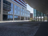 a empty parking area with large windows and a sidewalk in front of a building with lots of glass