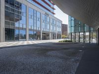 a empty parking area with large windows and a sidewalk in front of a building with lots of glass