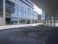 a empty parking area with large windows and a sidewalk in front of a building with lots of glass