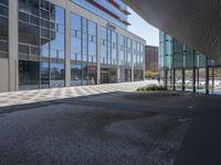 a empty parking area with large windows and a sidewalk in front of a building with lots of glass