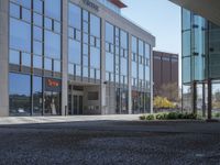 a empty parking area with large windows and a sidewalk in front of a building with lots of glass