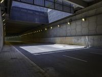 an empty parking lot with an orange light on the wall and street lights in front