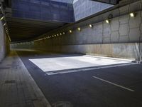 an empty parking lot with an orange light on the wall and street lights in front