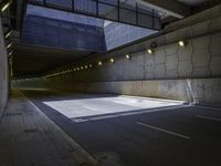 an empty parking lot with an orange light on the wall and street lights in front