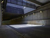 an empty parking lot with an orange light on the wall and street lights in front