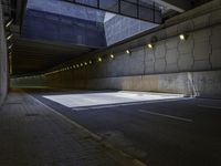 an empty parking lot with an orange light on the wall and street lights in front