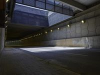 an empty parking lot with an orange light on the wall and street lights in front