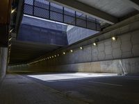 an empty parking lot with an orange light on the wall and street lights in front