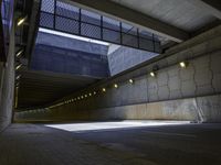 an empty parking lot with an orange light on the wall and street lights in front