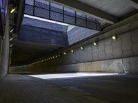 an empty parking lot with an orange light on the wall and street lights in front