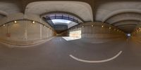 a 360 camera photograph showing a street in the background with arches over it and a smiling face painted on the floor