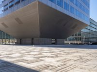 a large gray building sits on the street in front of a tall glass office building