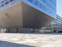 a large gray building sits on the street in front of a tall glass office building