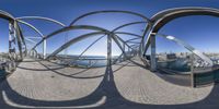 a large metal circular sculpture with a view of the city and harbor below it in a 3d style